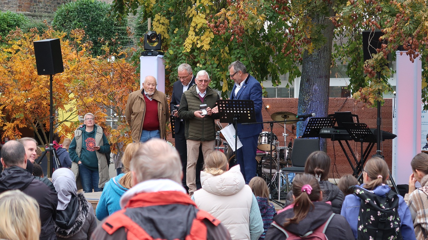 Oberbürgermeister Thomas Feser (re.) überreicht das Silberne Stadtsiegel an Carl Woog (2. v. re.).