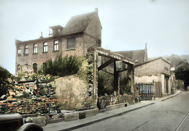 DieAnwesen Schmittstraße Nr. 66 (Ad. Wolf, Glaserei & Spiegel) und Nr. 64 (Tapetengeschäft Alex Barthel), nach der Beuchergasse das umzäunte Gelände des ehemaligen Gasthauses „Zum wilden Mann“ (Inhaber Josef Kühn) sowie daneben Lampen Henrich..