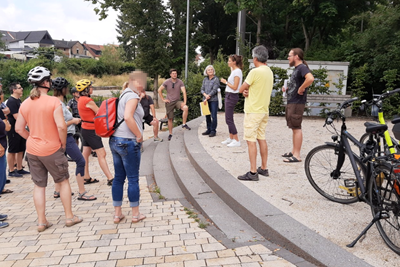 Zwischenstopp bei der Fahrradtour zu Energie- und Klimaschutzprojekten – Klimaschutzmanagerin Lisa Christmann (3.v.r.) erläutert die Details der jeweiligen Stationen