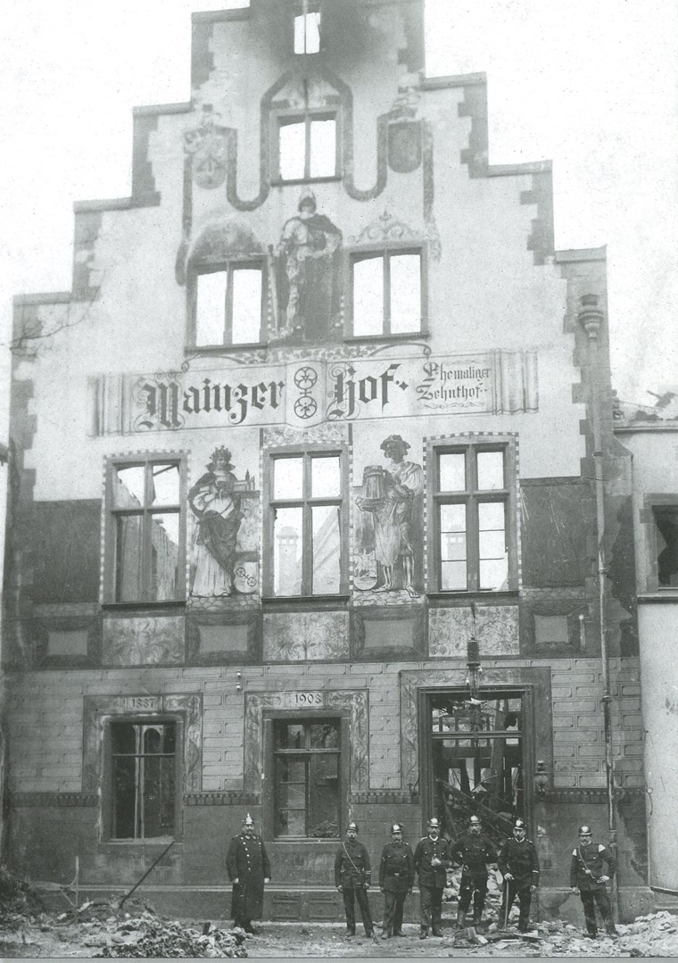 Nach dem Brand 1911 stand nur noch die Fassade des Gebäudes. Feuerwehrmänner posieren vor dem, was sie vor den Flammen retten konnten.