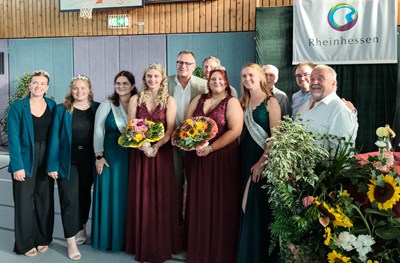 Oberbürgermeister Thomas Feser (hinten, Mitte) gratuliert den frisch gekrönten Eisweinmajestäten Lena Schmitt (rotes Kleid, re.) und Anna Pfeifer (rotes Kleid, li.). Mit dabei: Die Amtsvorgängerinnen, Binger Weinhoheiten und einige Dromersheimer Winzer.